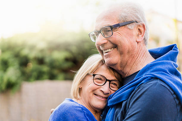 Senior couple embracing each other in backyard A photo of senior couple embracing each other. Happy retired man and woman wearing eyeglasses. They are smiling in backyard. 60 69 years stock pictures, royalty-free photos & images