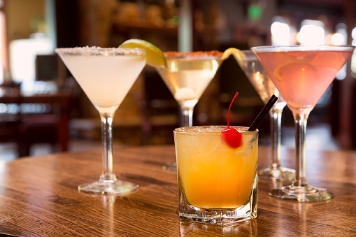 Four alcoholic drinks on a bar including exotic versions of a Martini and a Whisky Sour