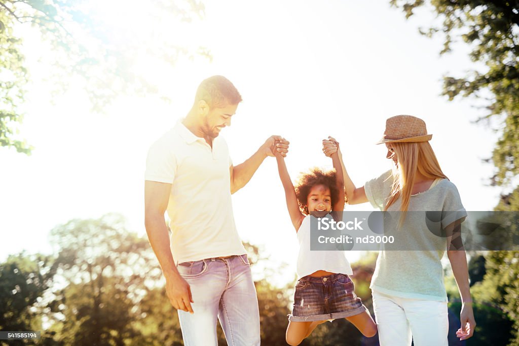 Mother and father swinging daughter Mother and father swinging daughter outdoors Adult Stock Photo