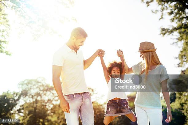 Mother And Father Swinging Daughter Stock Photo - Download Image Now - Adult, Baby - Human Age, Baby Girls