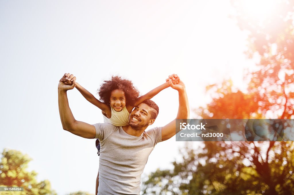 Father carrying daughter piggyback Father carrying daughter piggyback and being truly happy Family Stock Photo