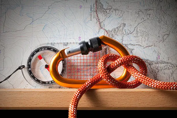 Compass,topographic map, karabiner and rope climbing on the shelf.