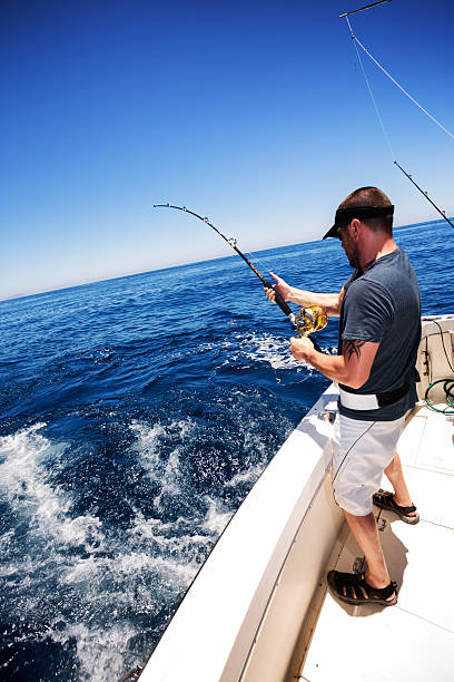 homme regardant gros poisson dans l " océan - big game fishing photos et images de collection