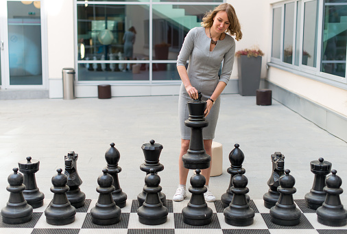 Woman playing outdoor chess game.