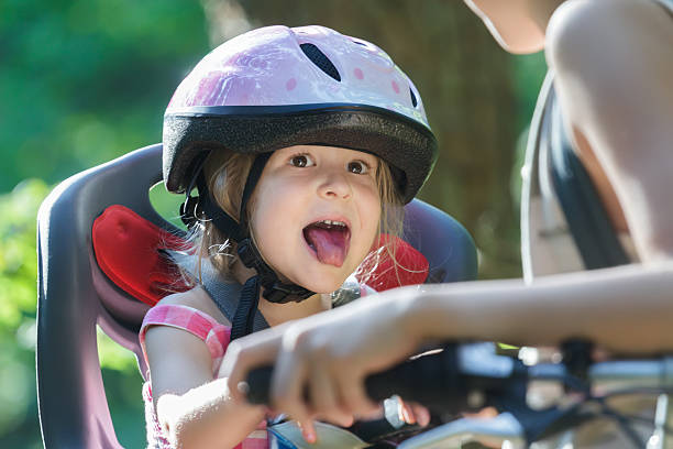 Ragazza che viaggia sul seggiolino per bambini e sporge la lingua - foto stock