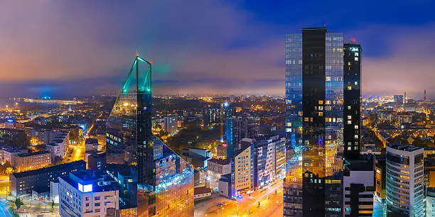 Aerial panorama of modern business financial district with tall skyscraper buildings illuminated at night, Tallinn, Estonia