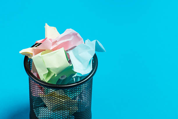 istock Colorful paper in a garbage bin on a blue surface 541592940