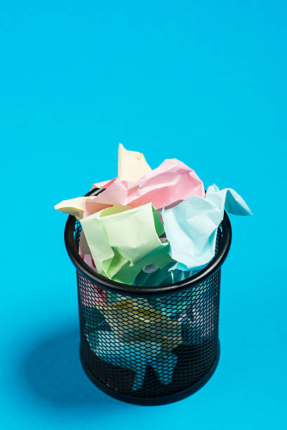 istock Colorful paper in a garbage bin on a blue surface 541593000