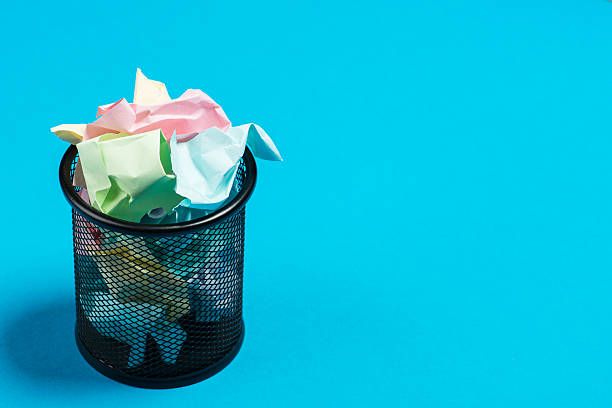 istock Colorful paper in a garbage bin on a blue surface 541593068