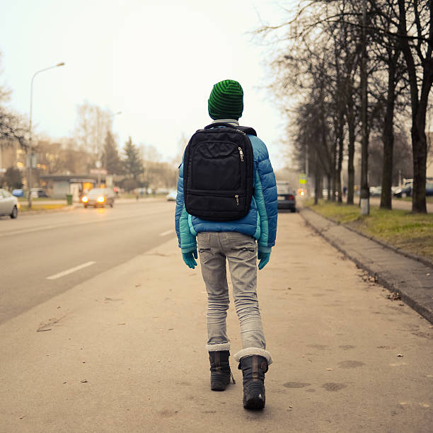 istock schoolboy alone in the street 541593174