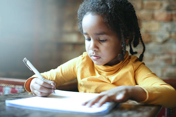 petite fille africaine écrivant. - schoolgirl little girls crayon human face photos et images de collection