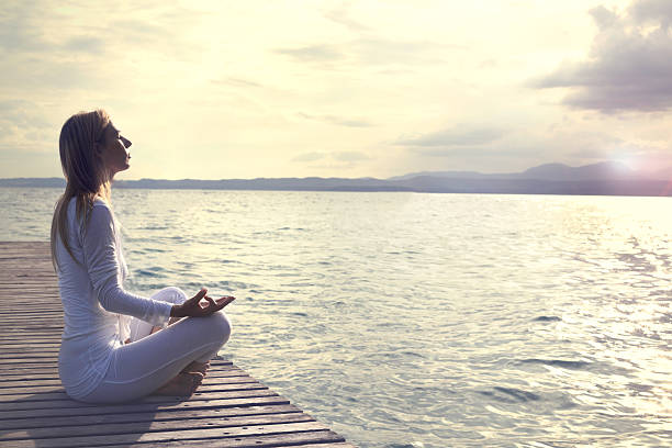 istock woman practicing yoga on the beach at sunset 541593996
