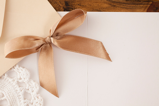 Letter, envelope, doiley, and brown ribbon on wooden table.  Decor.  Copyspace.