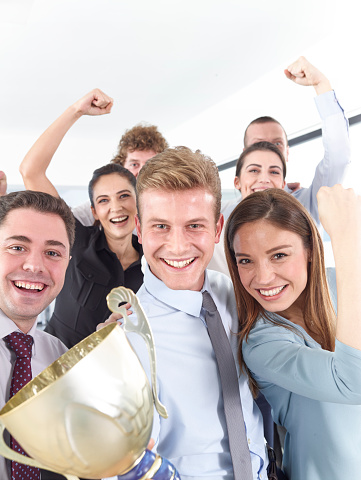 Cheerful group of businesspeople winning the cup with hands up.