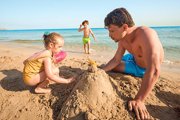 istock Father and children making sandcastle on sunny beach 541599088