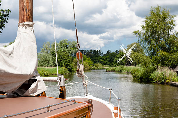 sailing boat and windmill on river on Norfolk Broads England