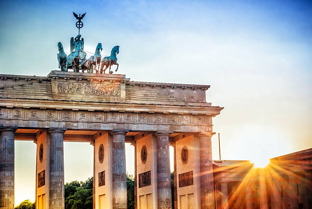 Color matching complementary palette from image of Brandenburg Gate in Berlin, Germany. Blue sky with pink, purple and grey clouds at sunset above golden illuminated gate.