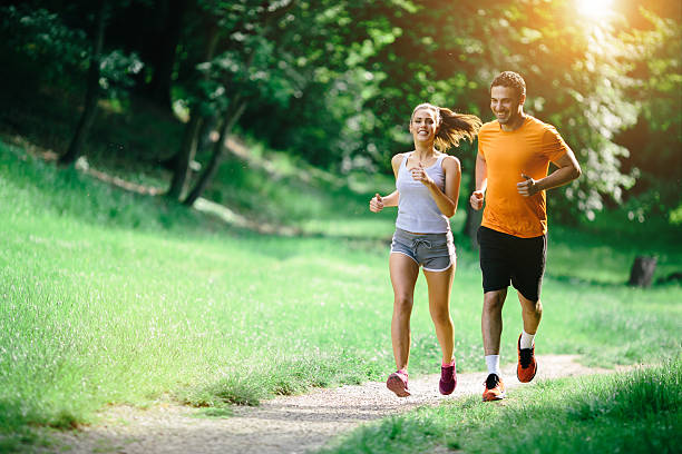 gesundes paar joggen in der natur - rennen körperliche aktivität stock-fotos und bilder