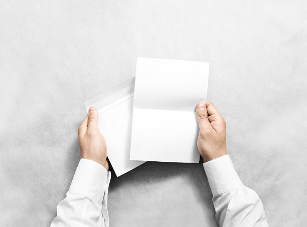 Hand holding white blank envelope and letter mockup, isolated.