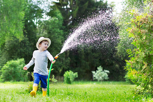 Watering Watering child watering garden hose stock pictures, royalty-free photos & images