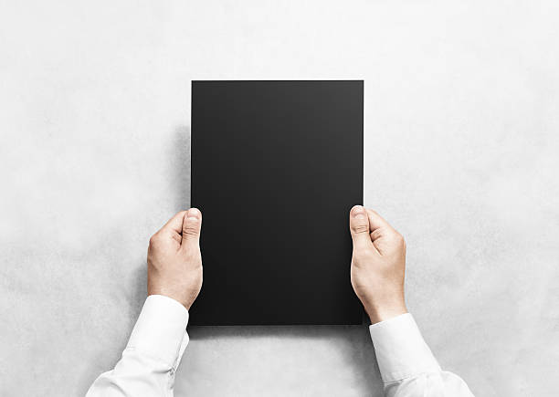 istock Hand holding black blank paper sheet mockup, isolated. 541611252