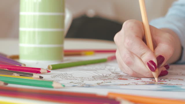 Woman coloring in adult coloring book at home