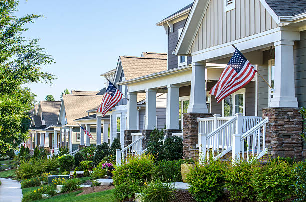 Patriotic Neighborhood American Flags hang from the front porch of a row of upscale Victorian-style homes in celebration of the upcoming holiday. Taken in the Summer in North Carolina, with beautiful morning sunlight to celebrate, Fourth of July, Labor Day, Memorial Day or Veteran's Day. Perfect image for any Summer project. front stoop photos stock pictures, royalty-free photos & images