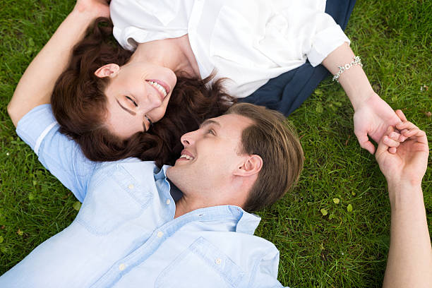 istock Couple looking at each other while lying on the grass 541824482