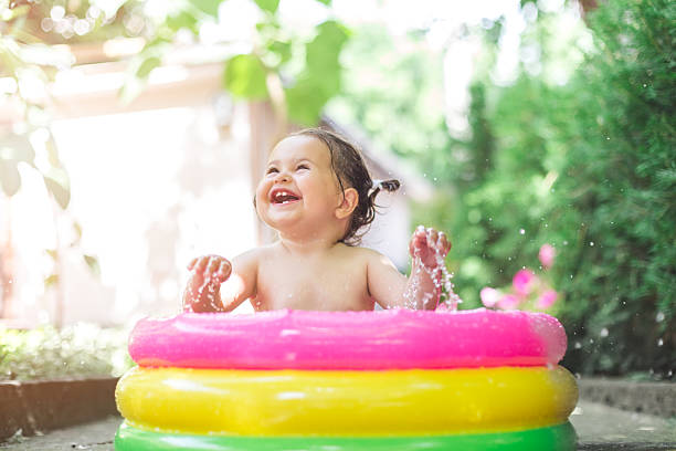 one year old baby girl is playing , splashing in the pool . baby is first time in pool and she is very happy and excited
