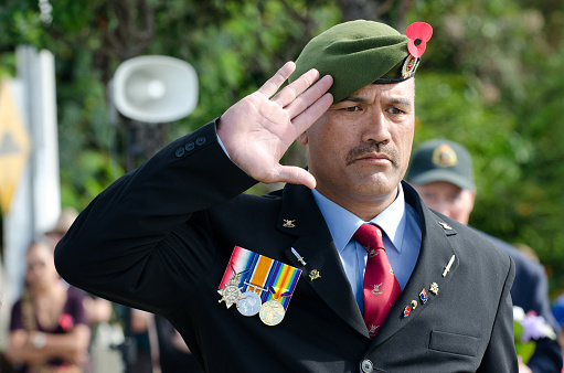 Mangonui, New Zealand - April 25, 2012: New Zealand Maori veteran soldier stands an salutes during an Anzac Day war Memorial Service.