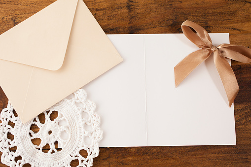 Letter, envelope, doiley, and brown ribbon on wooden table.  Decor.  Copyspace.