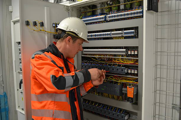 Electrician connecting wires AN electrician connecting wires in a control panel Where Do Electrical Power Engineers Use PLCs stock pictures, royalty-free photos & images
