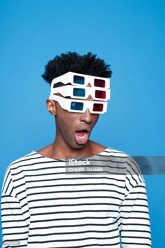 Surprised afro american guy wearing 3d glasses Surprised afro american young man wearing striped top and 3d glasses. Studio portrait, blue background. 3-D Glasses Stock Photo