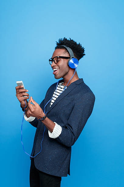 アフリカ系アメリカ人男性スマートフォンヘッドフォンを使用して着用 - smart casual side view one person success ストックフォトと画像