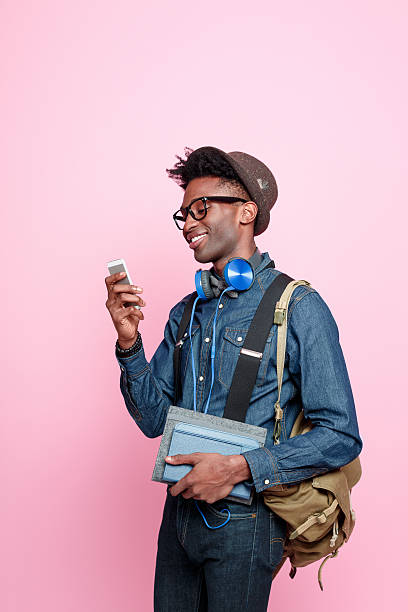 étudiant afro-américaine à l'aide d'un smartphone - men smiling headphones individuality photos et images de collection