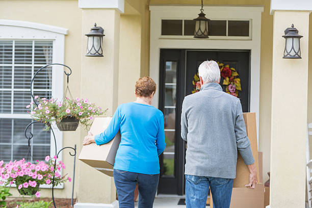 Senior couple carrying boxes to front door of house Rear view of a senior couple carrying large cardboard boxes to the front door of a house. They are moving into their new home. man touching womans buttock stock pictures, royalty-free photos & images