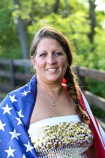 istock Woman Poses For Camera With American Flag Draped Around Shoulders 541837716