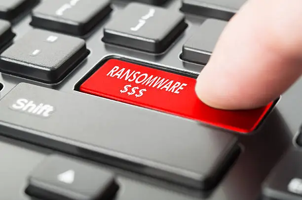 Photo of Ransomware written on keyboard button with finger pressing on it