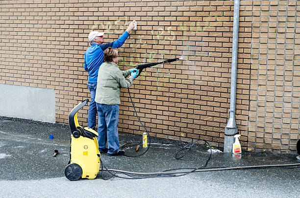 Man and woman cleaning graffiti on their brick wall Sherbrooke, Canada - June 11, 2016: Man and woman cleaning graffiti on their brick wall using brush, cleaner and pressure water hose during a day of springtime. sherbrooke quebec stock pictures, royalty-free photos & images