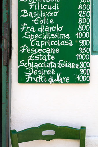 Lipari, Sicily, Italy - June 2, 2016: Typical Aeolian Island cuisine as described on a menu handwritten in chalk on an outdoor rustic blackboard. Lipari is a World Heritage site, the largest of the Aeolian Islands.