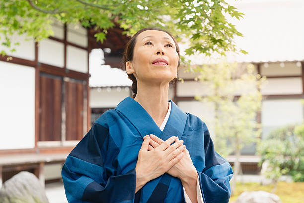 louva japonês mulher olhando para cima com alegria templo de quioto, japão - spirituality hand on heart meditating women - fotografias e filmes do acervo