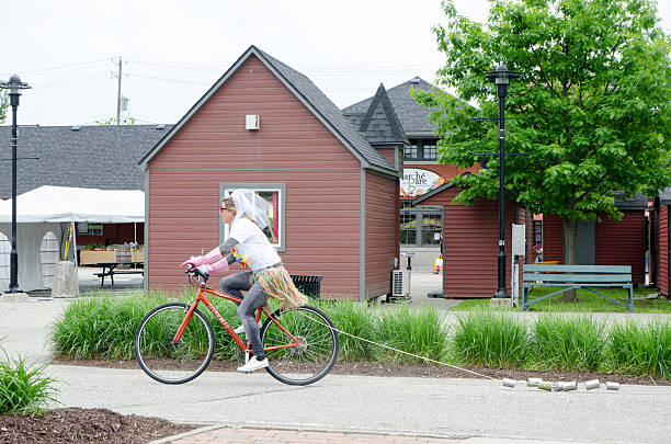 Woman having her bachelorette party costumed on a bicycle Sherbrooke, Canada - June 11, 2016: Woman having her bachelorette party costumed on a bicycle and dragging tin cans in a park. She wears a wedding gown, colorful sunglasses, This is outside during a day of springtime. sherbrooke quebec stock pictures, royalty-free photos & images