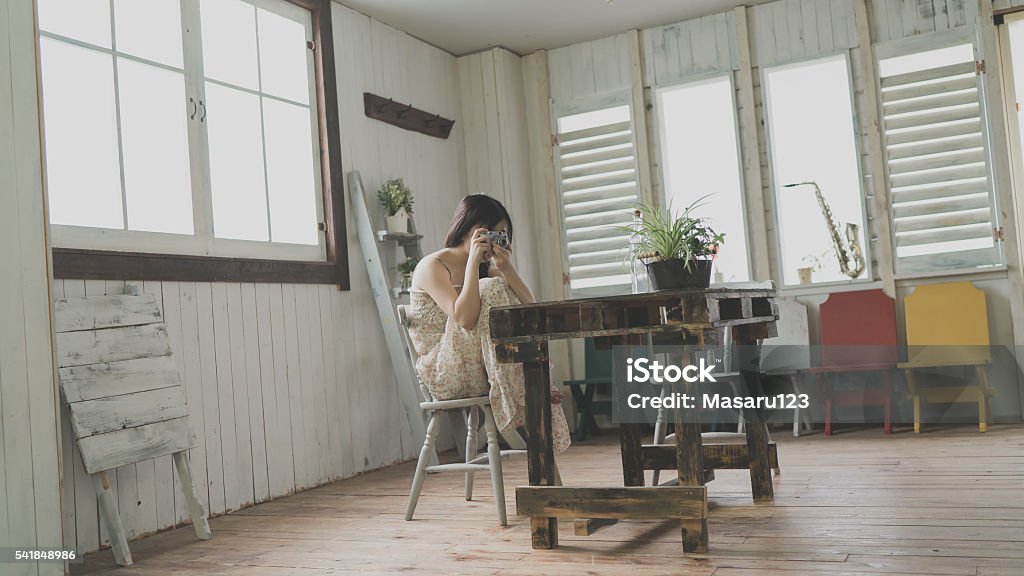 Young woman taking photos in a room A young woman is holding a camera and taking photos. 20-29 Years Stock Photo