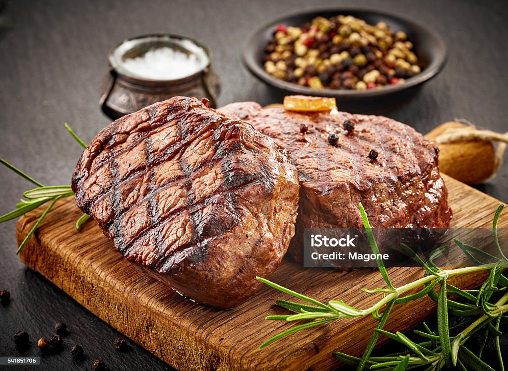 grilled beef steaks grilled beef steaks with spices on wooden cutting board Steak Stock Photo