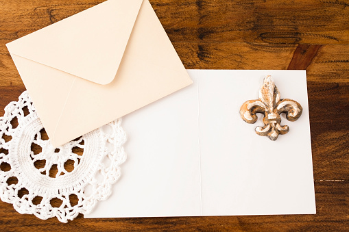 Letter, envelope, doiley, and fleur de lis on wooden table.  Decor.  Copyspace.