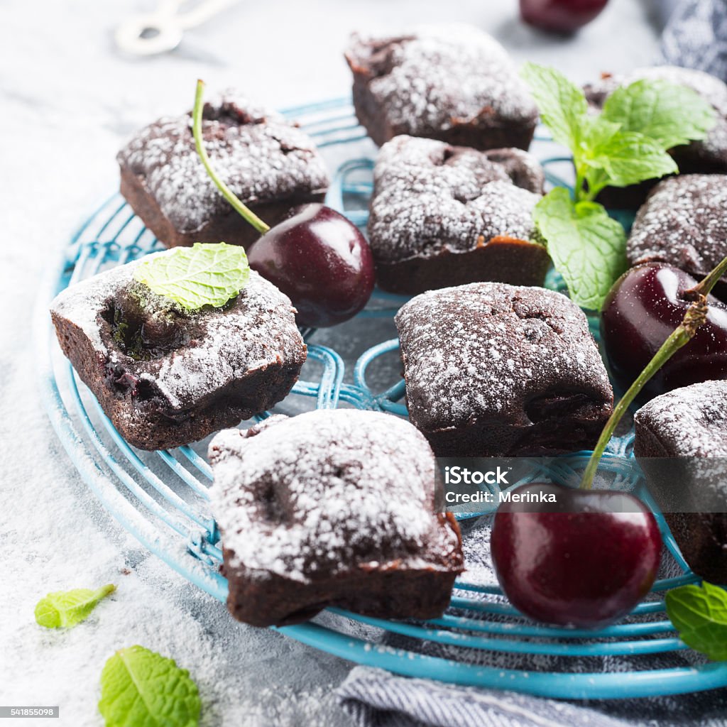 Homemade chocolate cherry brownie cake Homemade chocolate cherry brownie cake decorated with powdered sugar on blue rack on gray background. Healthy diet food concept. Selective focus. Backgrounds Stock Photo