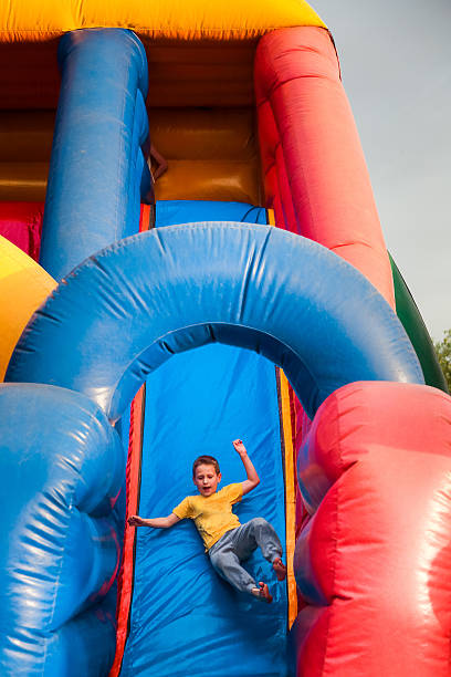7 ans garçon joue sur gonflable château gonflable slide - inflatable slide sliding child photos et images de collection