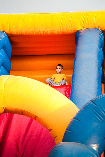 istock 7 years boy sittng on inflatable bouncy castle slide 541857242