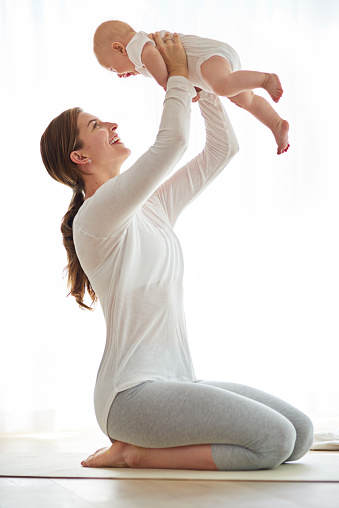 Shot of a young woman working out with her baby boy at home