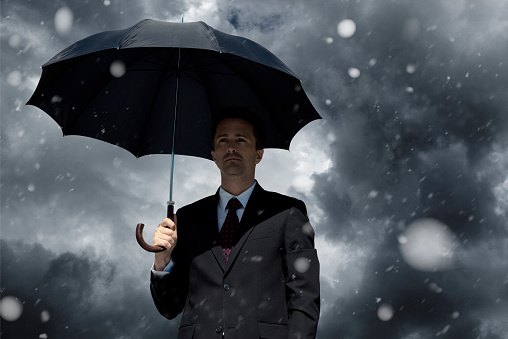 Businessman with umbrella - crisis concept 